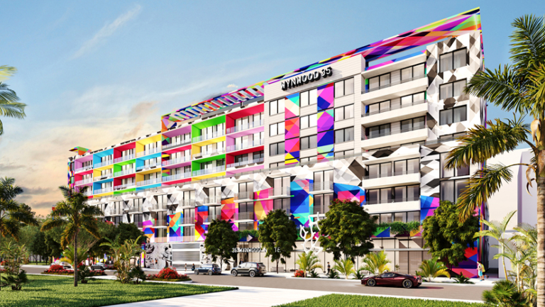 A multi-story building with colorful geometric patterns on the facade, palm trees in front, and parked cars along the street.